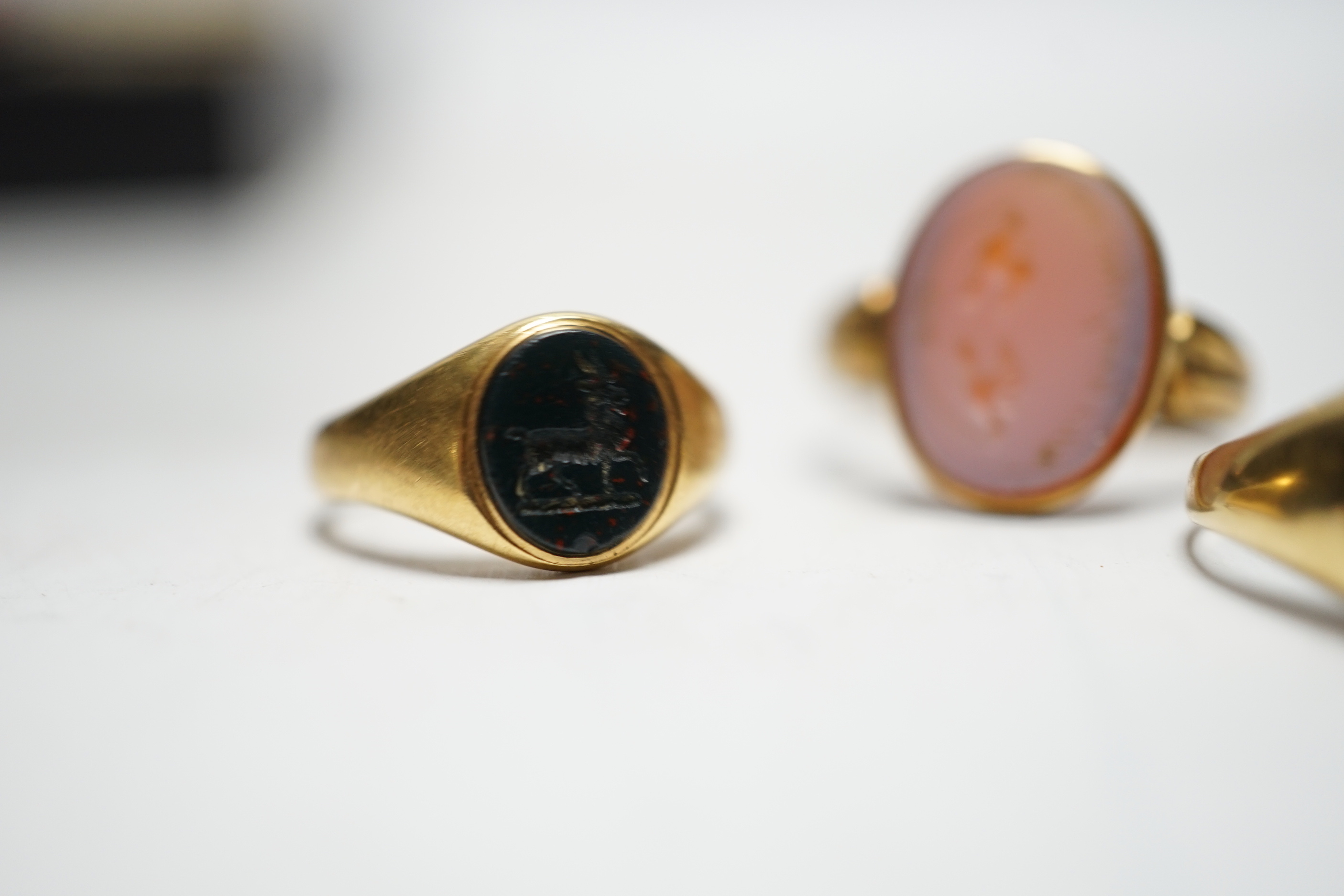 A Victorian yellow metal and sardonyx set oval seal ring, the matrix carved with two birds and motto, size O, together with two early 20th century yellow metal and chalcedony set child's signet rings, gross weight 9.7 gr